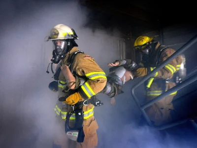 Two firefighters in yellow uniforms in a smokey room