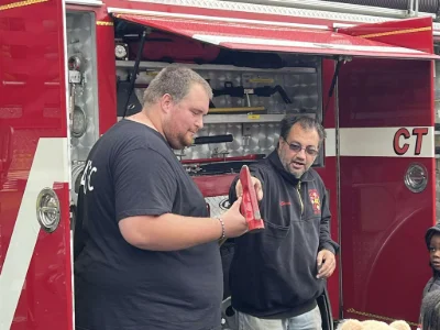 A firefighter handing an axe to another volunteer firefighter